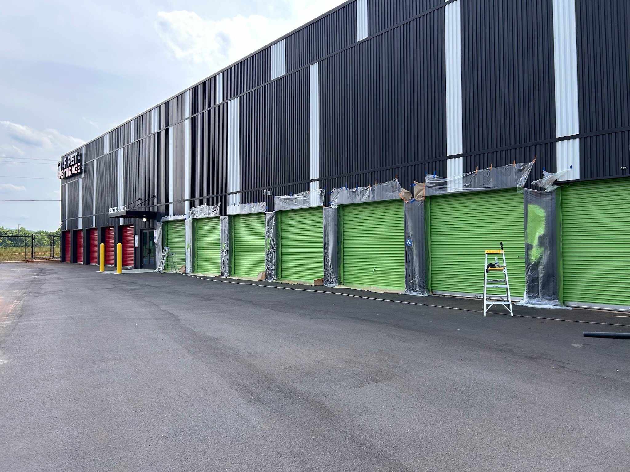 Commercial repaint of roll-up doors at a storage facility, masked and painted green